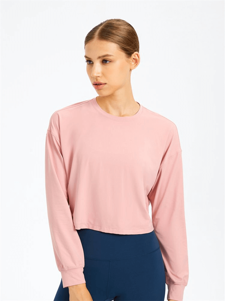 Woman wearing pink stylish sport short women's sweatshirt with long sleeves for yoga, made of breathable spandex.